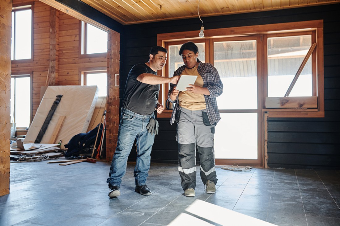 a contractor and an architect discussing something on an ipad at a house renovation
